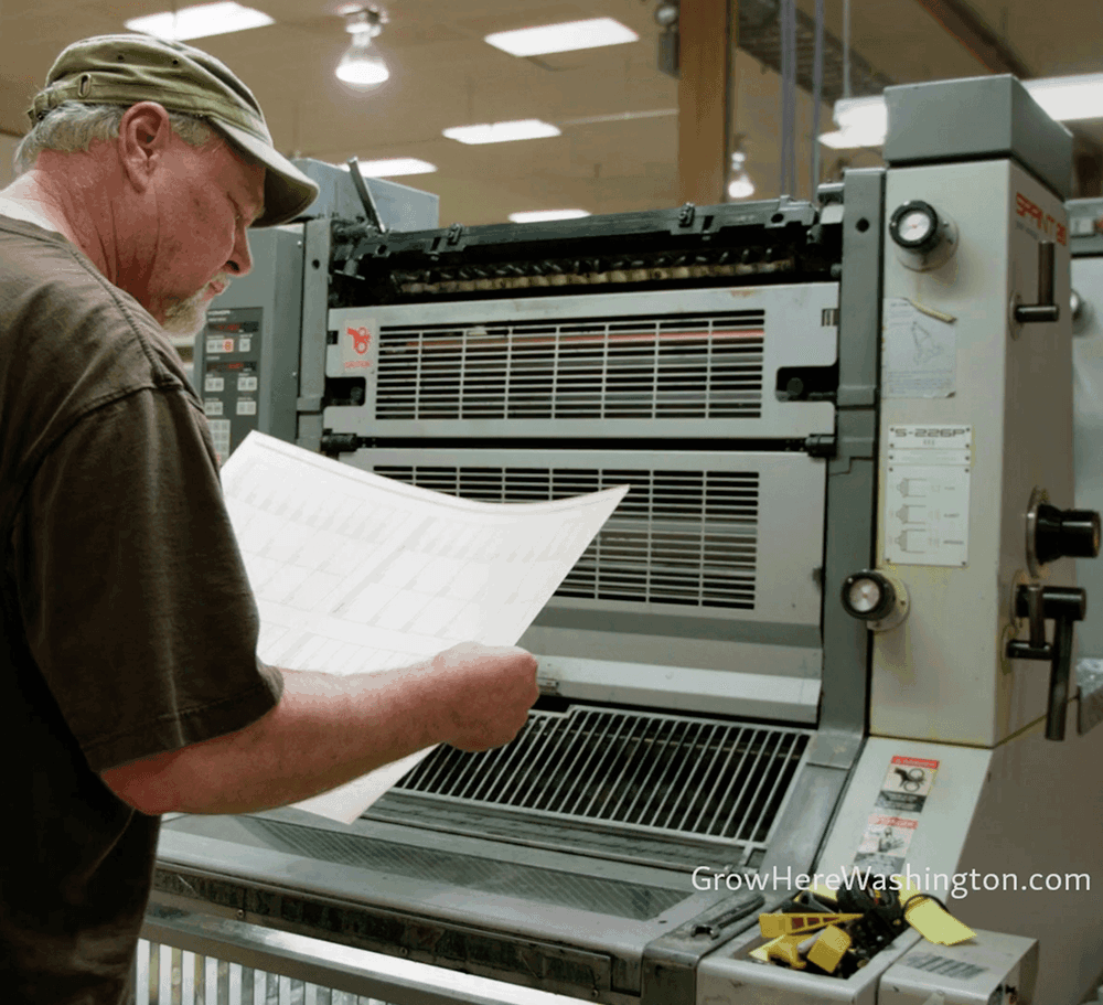 Pressmen looking at freshly printed sheet.