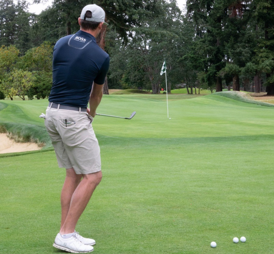 Killmer swining an iron towards flag in distance.