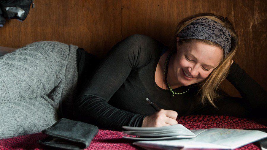 Adventure writer journaling in a stapled notebook.