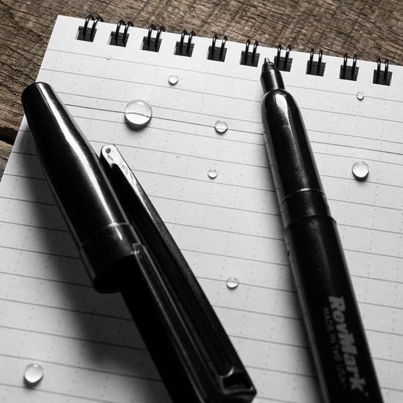 All weather pen laying on a notebook with ink written through water.