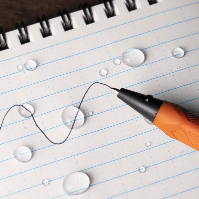 All-weather pen siting on notebook, ink written through water.