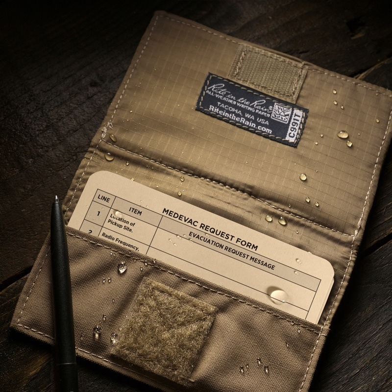 Wet Combat card in an index card wallet, all weather pen resting on wallet