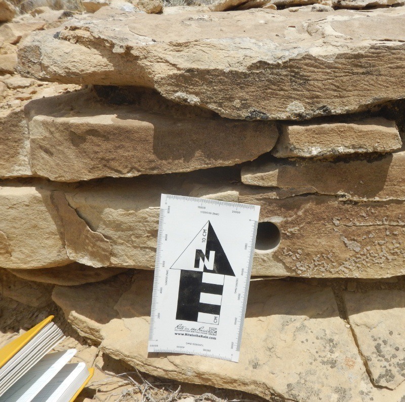 Rite in the Rain book and photo scale measuring a drill hole in rock.