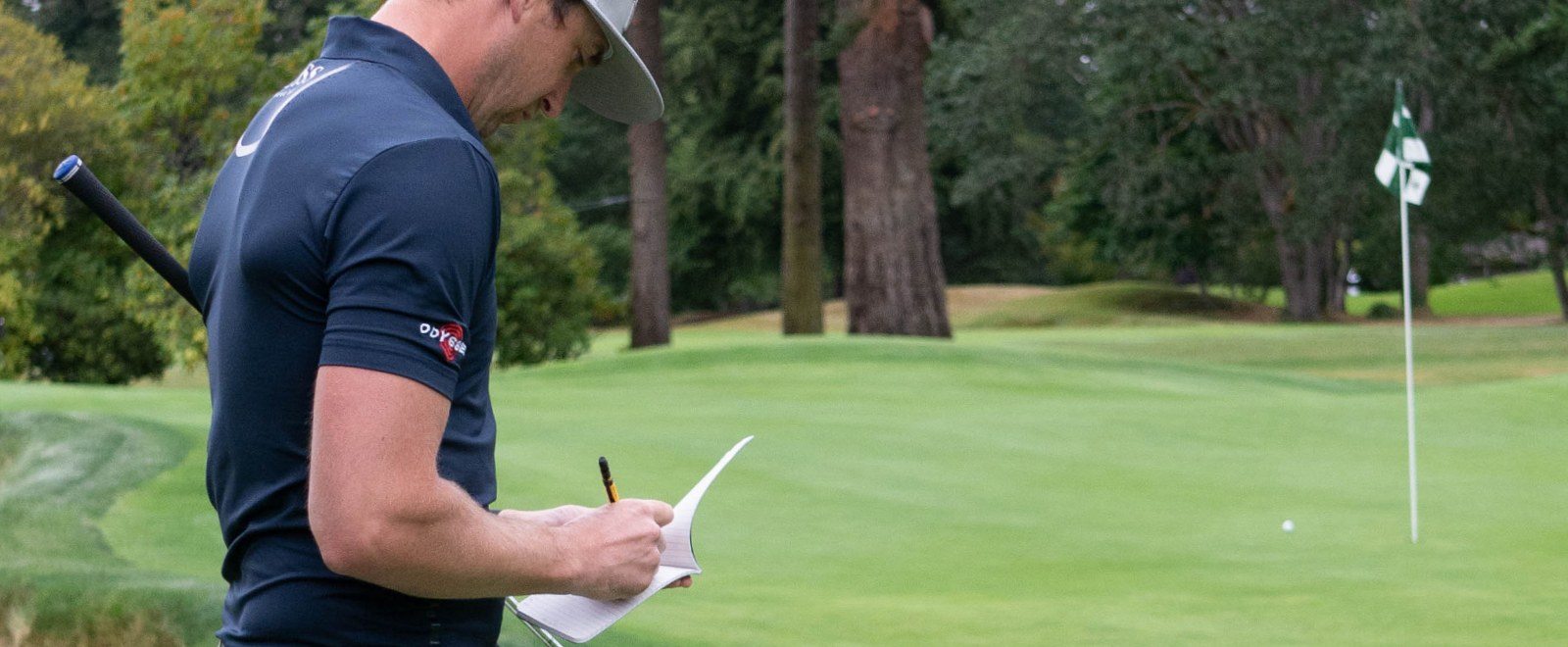 Pro Golfer writing notes in all weather golf notebook using a mechanical pencil