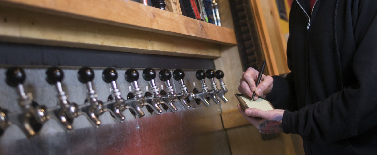 Bartender using index cards and wallet to record tap information.