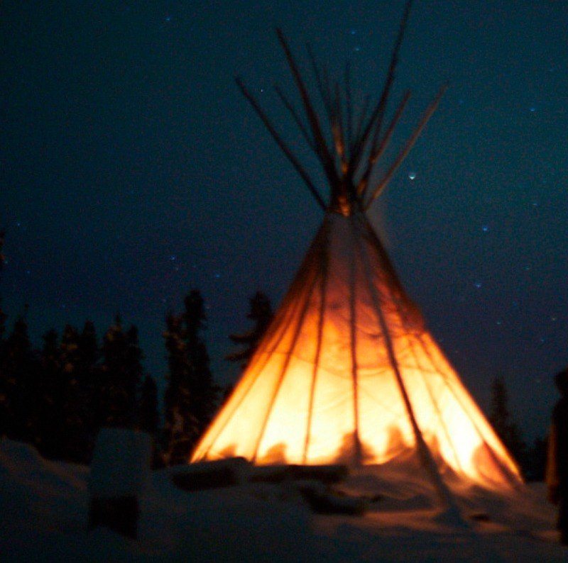 Retreat teepee glowing at night with a silhouette of the retreat's participants.