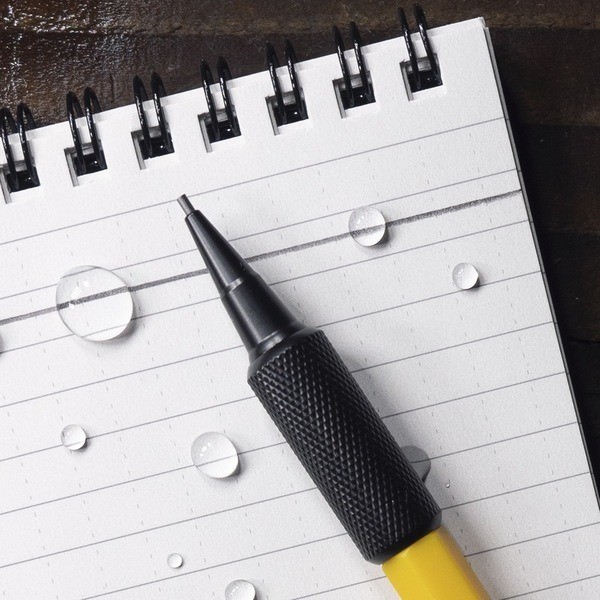 Mechanical pencil resting on notebook with writting through water drops.