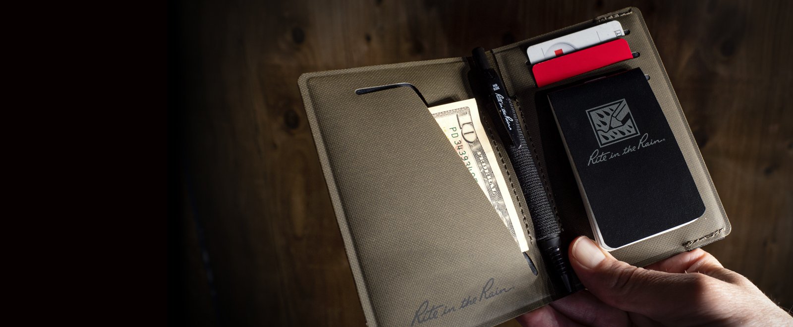 Hand holding open wallet filled with contents.