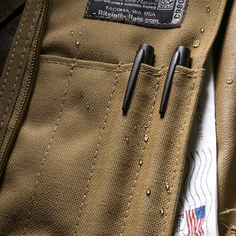 All weather pens stored in instrument pockets of a cordura fabric notebook cover. 
