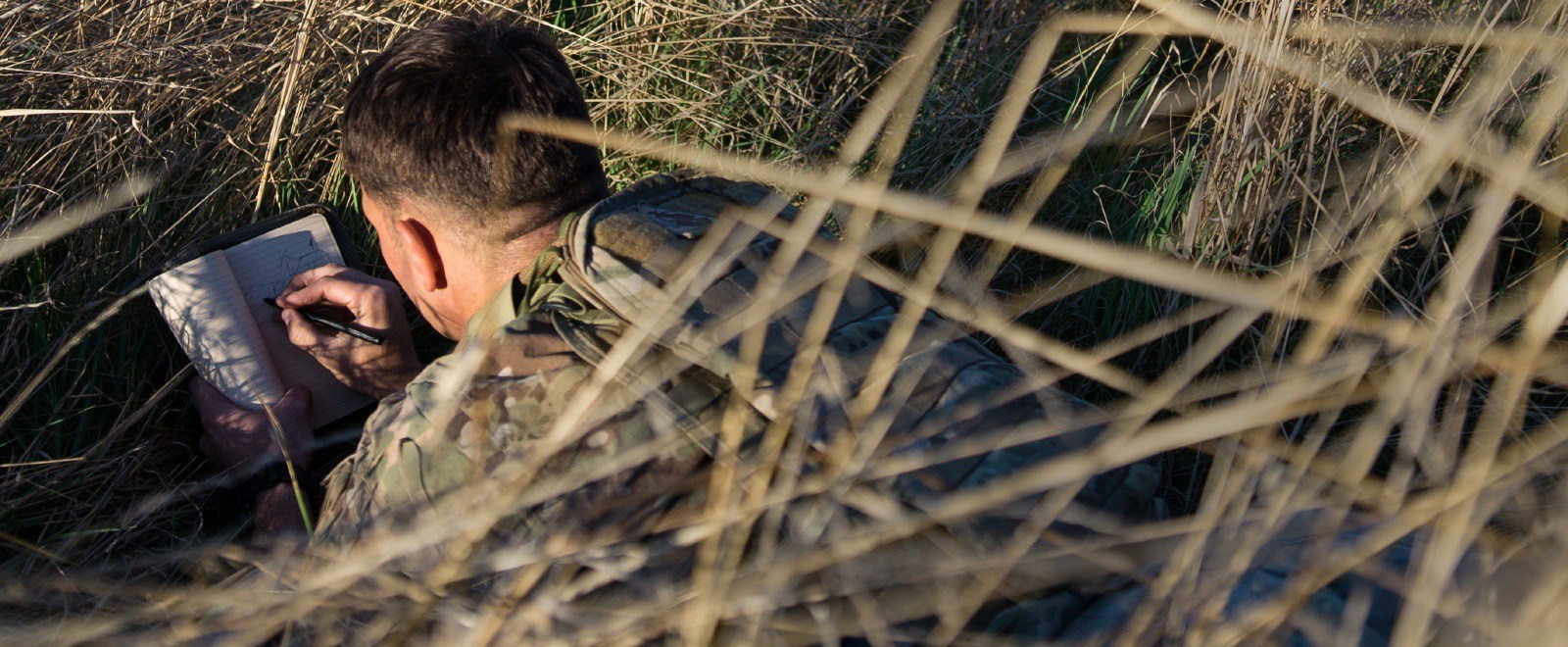 Person in armed forces writing in a tactical field book with an all weather pen.