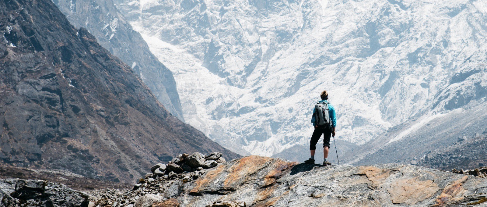 mountaineer on high ledge looking at glacier