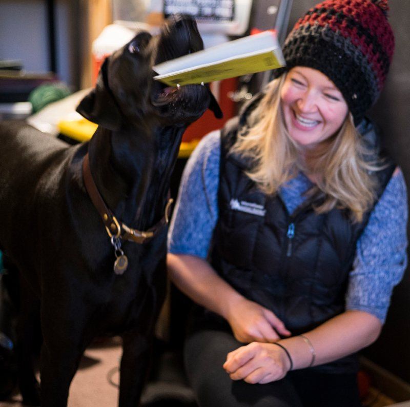 Mountaineer laughing as her dog takes her notebook.