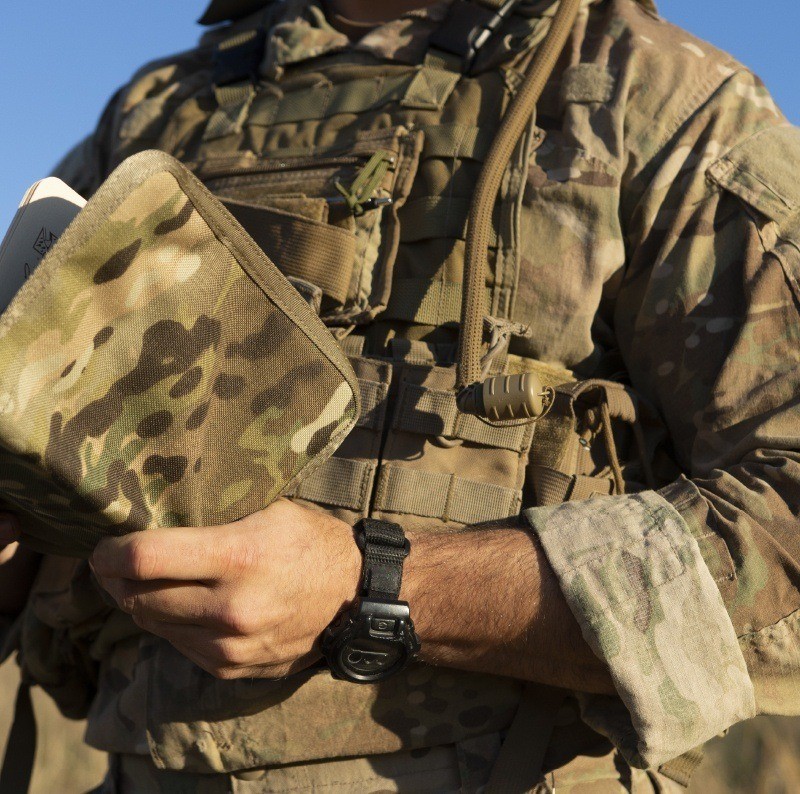 Person in the armed forces holding a multicam cover with a field book.